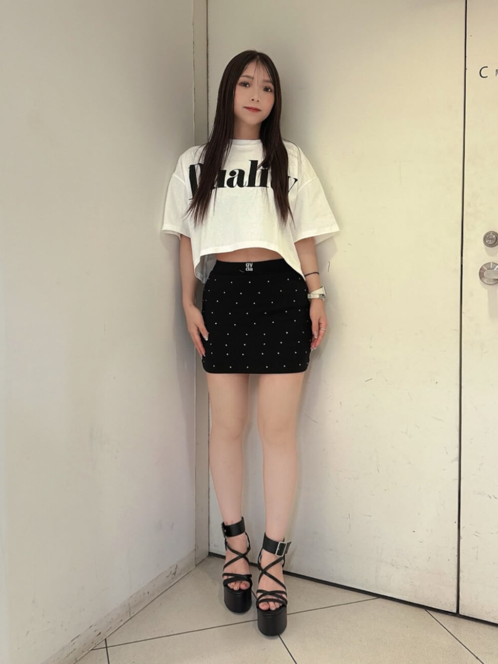 ブラック系のスカート、ホワイト系のTシャツ/カットソー、ブラック系のサンダルを着用したレディースの夏コーディネートの1枚目の写真