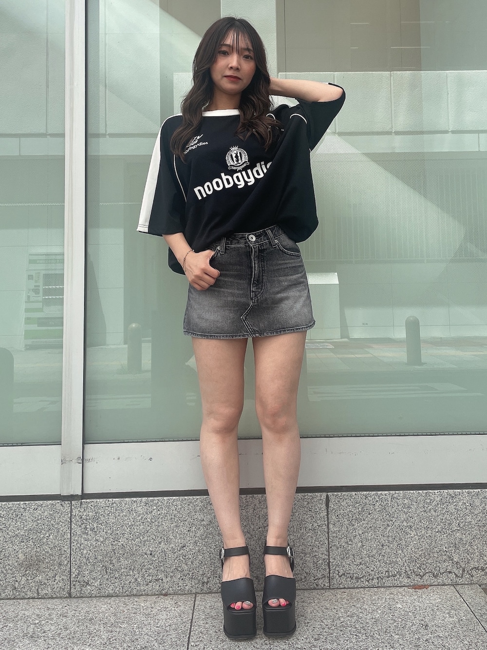 ブラック系のデニムスカート、ブラック系のTシャツ/カットソー、ブラック系のサンダルを着用したレディースの夏コーディネートの1枚目の写真