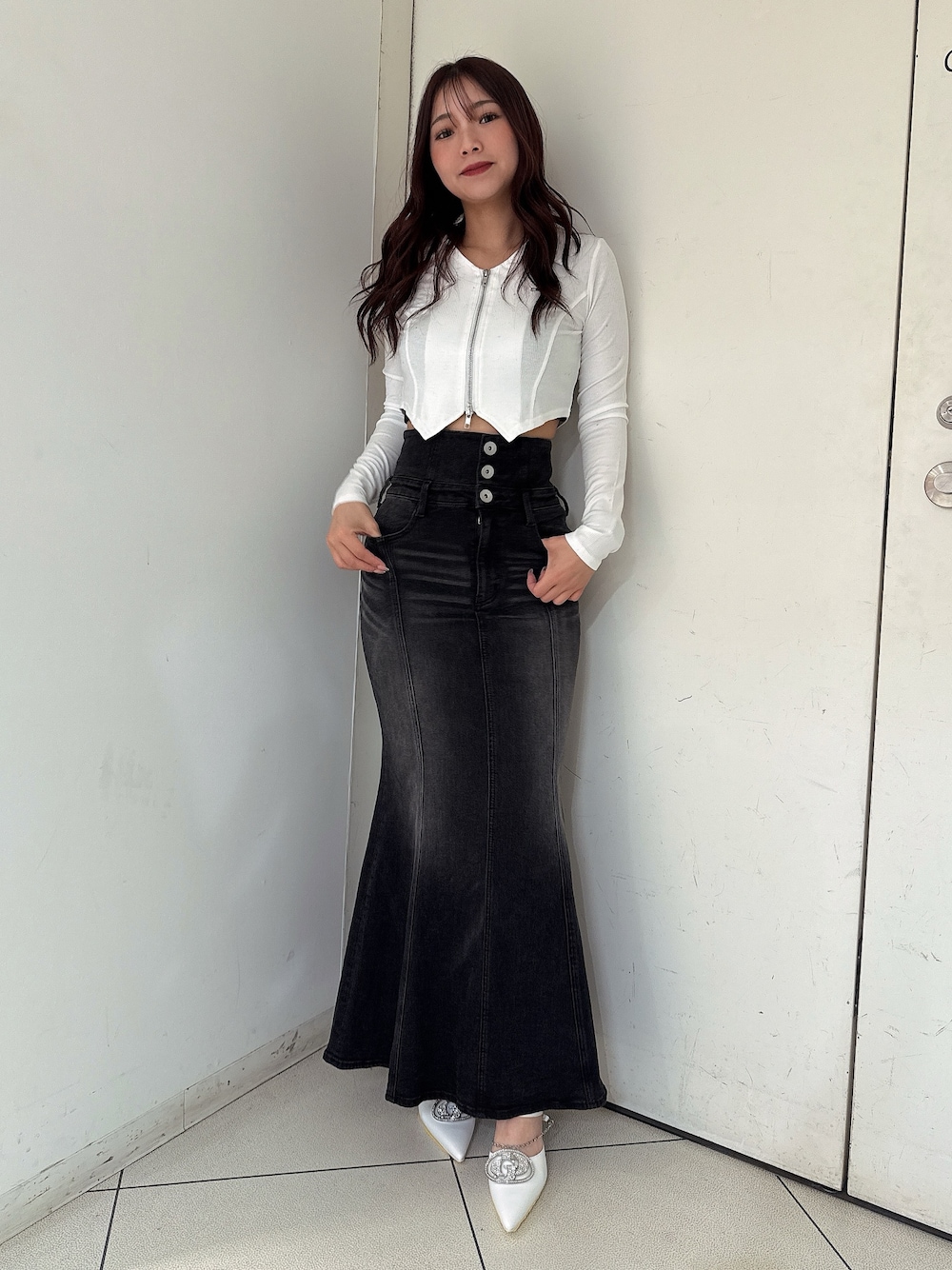 ブラック系のデニムスカート、ブラック系のTシャツ/カットソー、ホワイト系のパンプスを着用したレディースの秋コーディネートの1枚目の写真