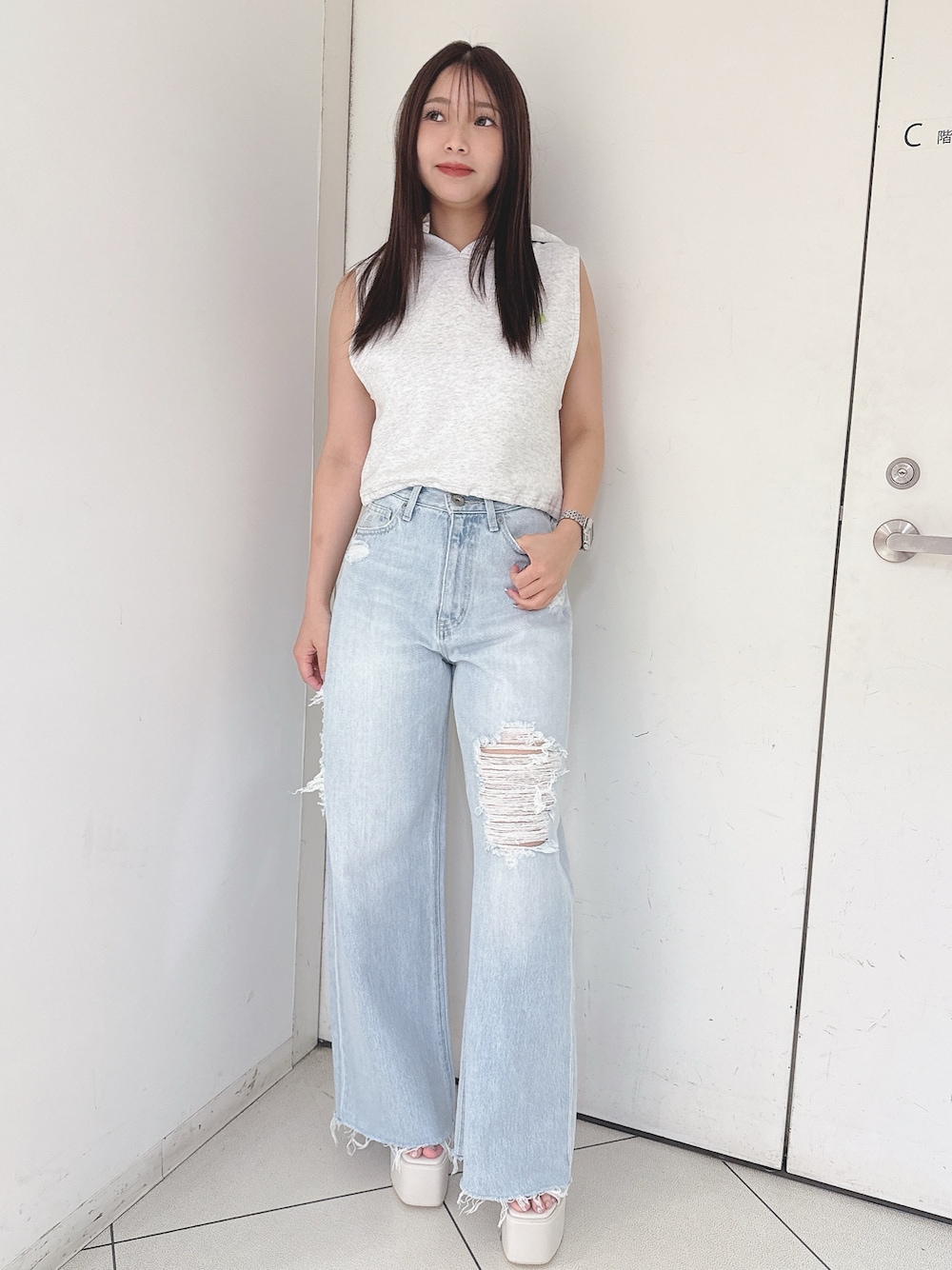 グレー系のパーカー、ブルー系のデニムパンツ、ホワイト系のサンダルを着用したレディースの夏コーディネートの1枚目の写真