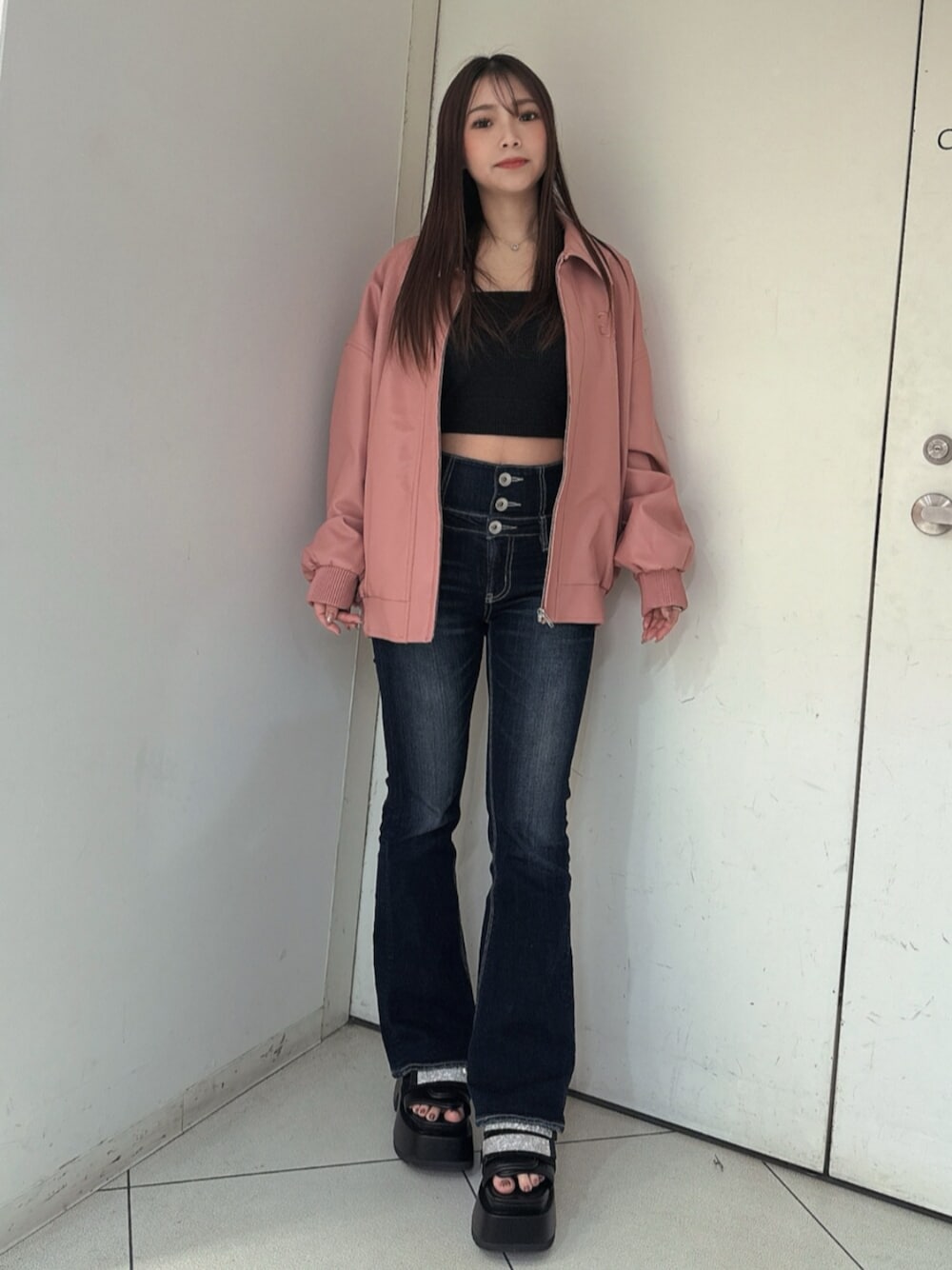 ブルー系のデニムパンツ、ブラック系のサンダル、ピンク系のブルゾンを着用したレディースの春コーディネートの1枚目の写真