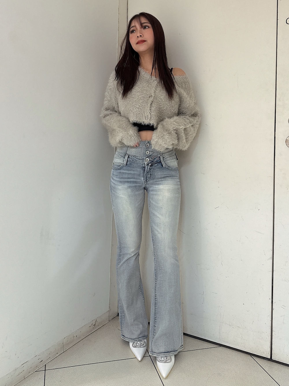 ブルー系のデニムパンツ、ホワイト系のパンプス、ベージュ系のカーディガン/ボレロを着用したレディースの秋コーディネートの1枚目の写真