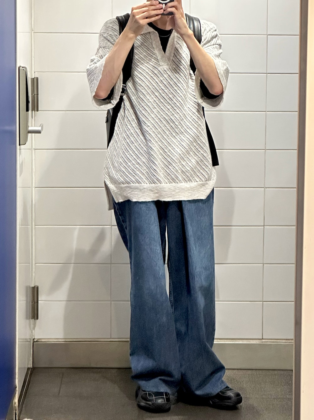 グレー系のポロシャツ、ブルー系のデニムパンツ、ブラック系のスニーカーを着用したメンズの夏コーディネートの1枚目の写真