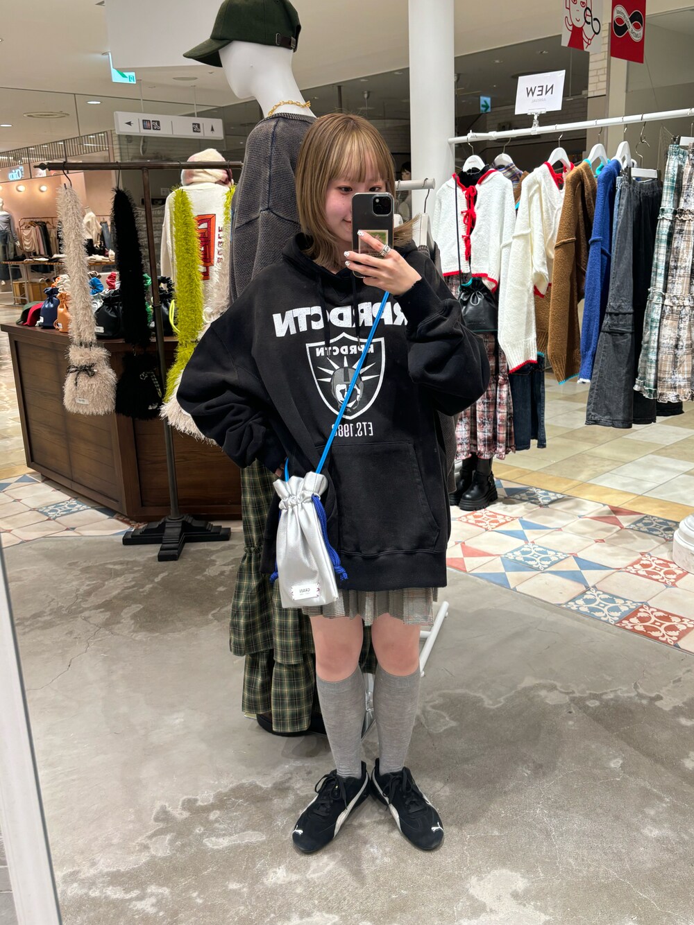 ブラック系のパーカー、グレー系のスカート、シルバー系のショルダーバッグを着用したレディースの冬コーディネートの1枚目の写真