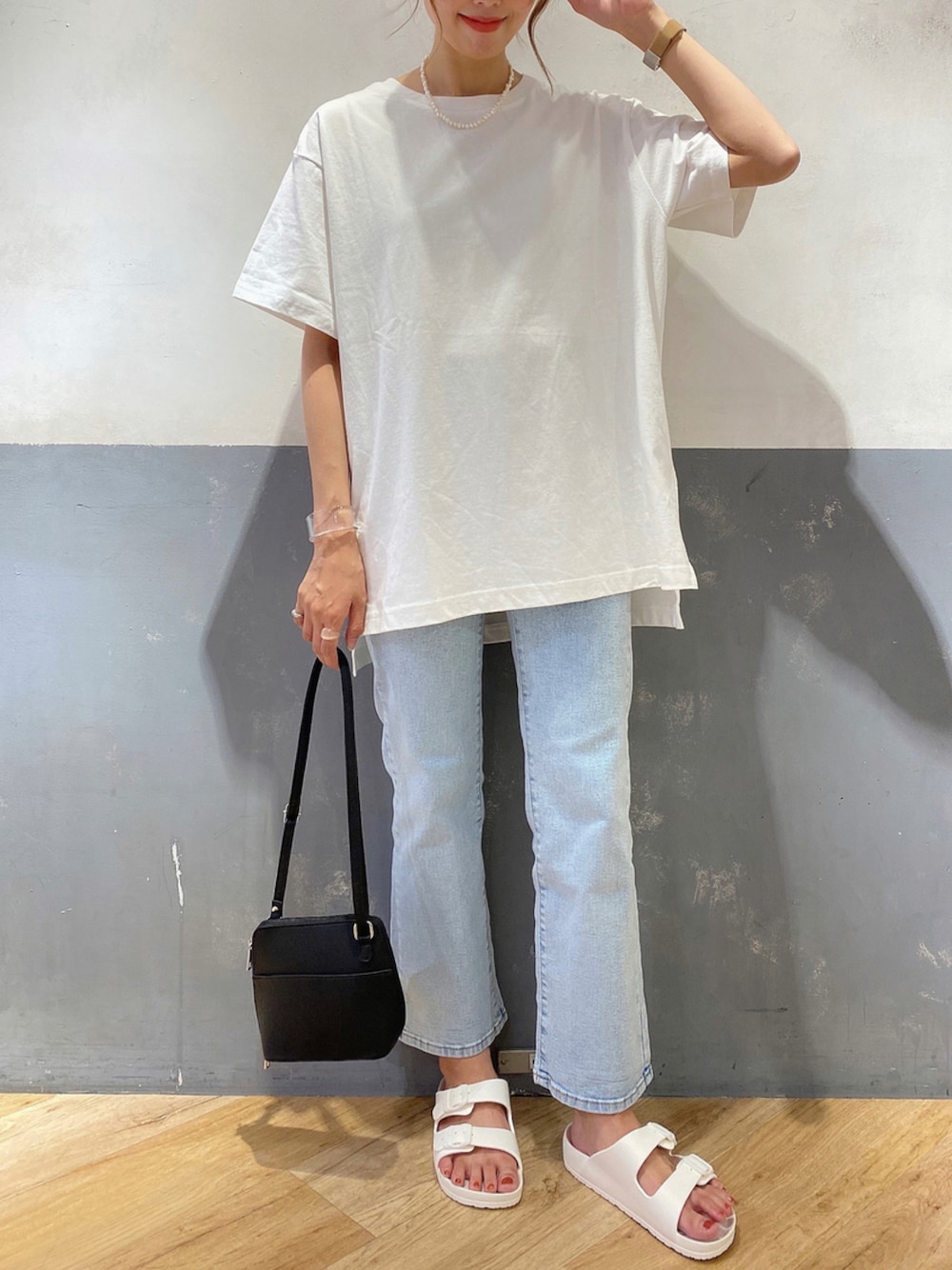 ホワイト系のサンダル、ブルー系のデニムパンツ、ブラック系のショルダーバッグを着用したレディースの夏コーディネートの1枚目の写真