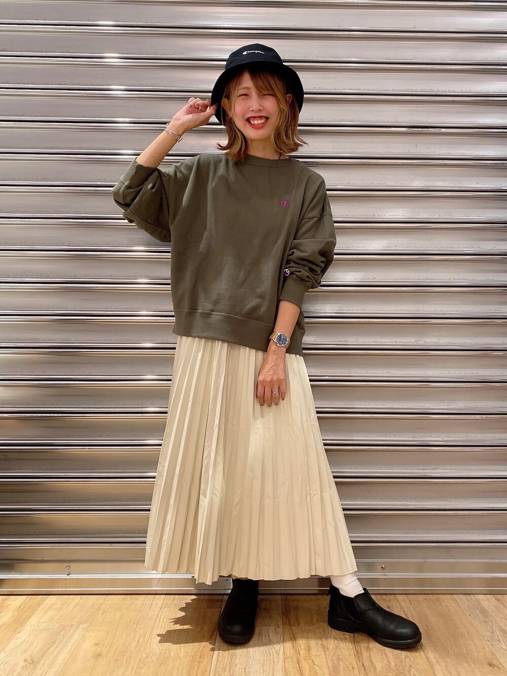 グリーン系のスウェット、ホワイト系のスカート、ブラック系のハットを着用したレディースの秋コーディネートの1枚目の写真