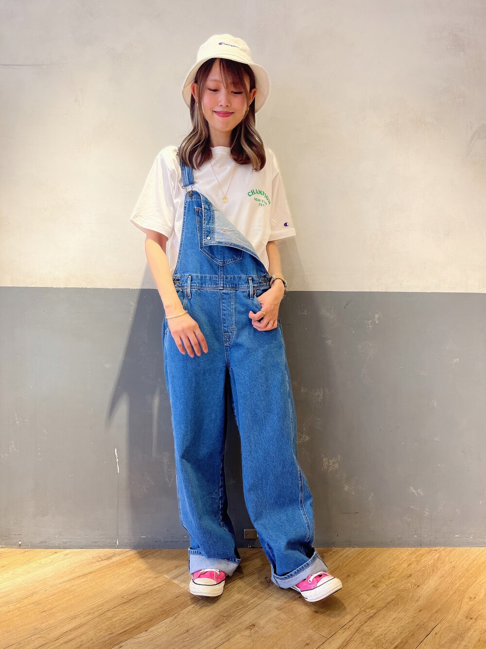 ブルー系のサロペット/オーバーオール、ホワイト系のTシャツ/カットソー、ブラック系のハットを着用したレディースの春コーディネートの1枚目の写真