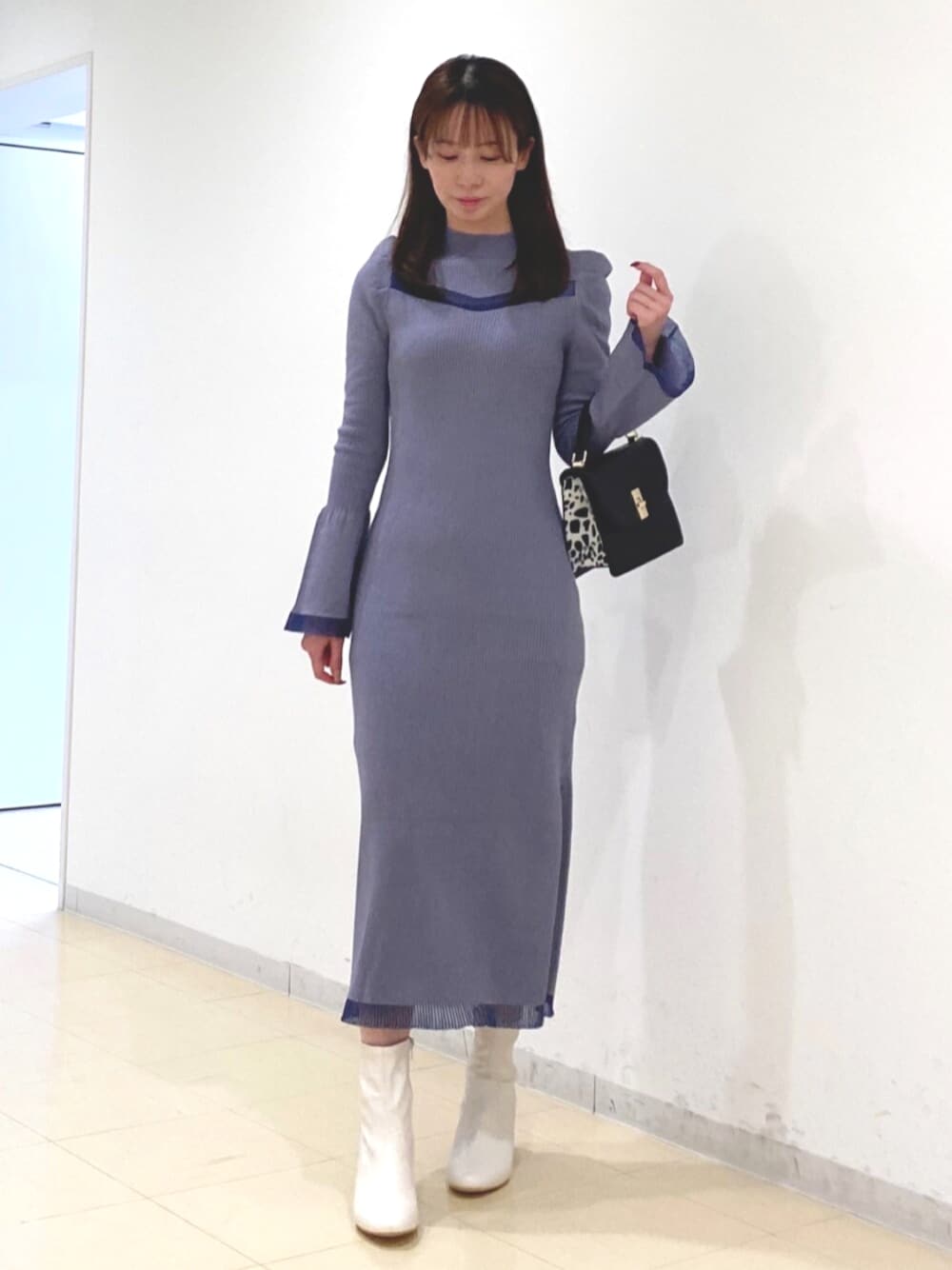 ホワイト系のブーツ、ブルー系のワンピース、ブラック系のハンドバッグを着用したレディースの冬コーディネートの1枚目の写真