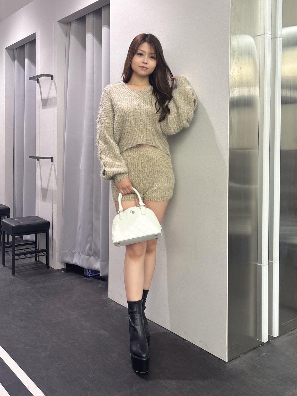 ベージュ系のその他パンツ、ベージュ系のニット/セーター、ホワイト系のハンドバッグを着用したレディースの秋コーディネートの1枚目の写真