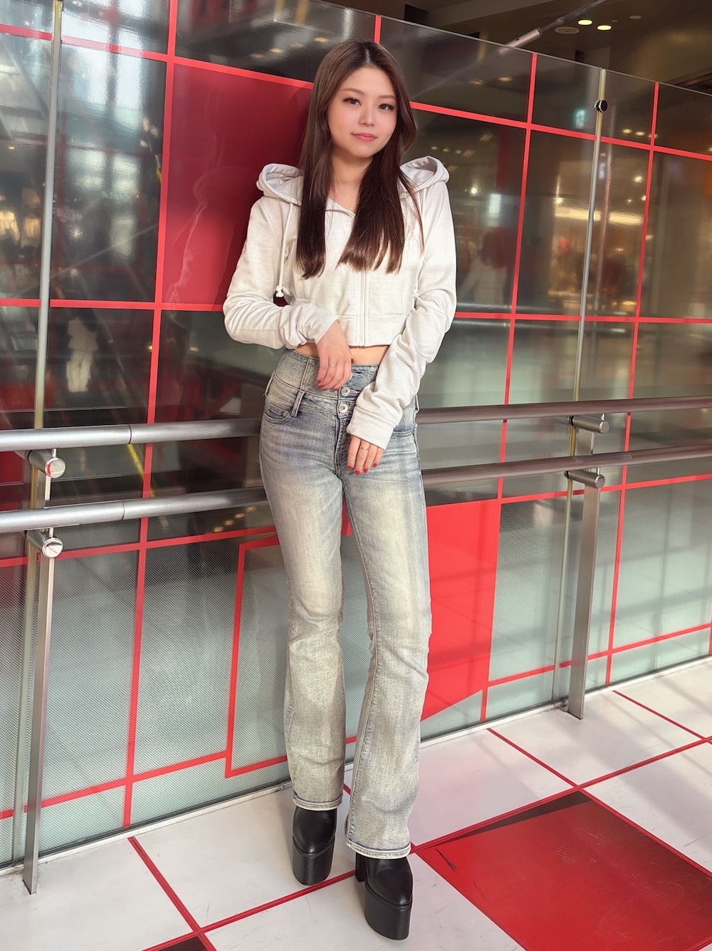 ホワイト系のパーカー、ブルー系のデニムパンツ、ブラック系のブーツを着用したレディースの冬コーディネートの1枚目の写真