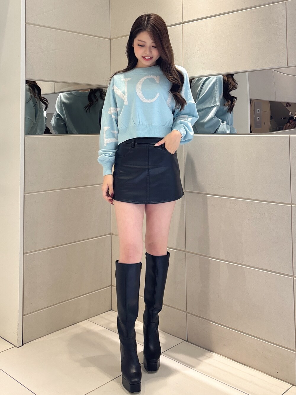 ブルー系のニット/セーター、ブラック系のスカート、ブラック系のブーツを着用したレディースの冬コーディネートの1枚目の写真