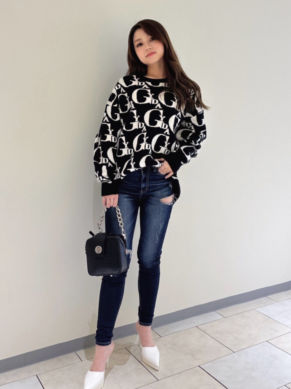 ホワイト系のパンプス、ブラック系のニット/セーター、ブルー系のデニムパンツを着用したレディースの冬コーディネートの1枚目の写真