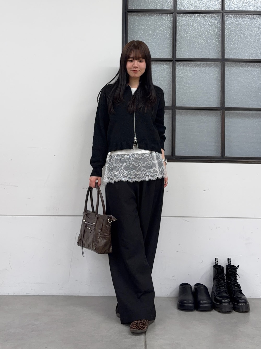 ブラウン系のショルダーバッグ、ブラック系のスラックス、ホワイト系のTシャツ/カットソーを着用したレディースの春コーディネートの1枚目の写真