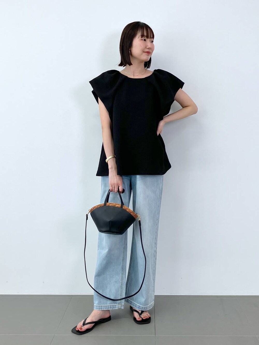 ブラック系のシャツ/ブラウス、ブラック系のかごバッグ、ブルー系のデニムパンツを着用したレディースの夏コーディネートの1枚目の写真