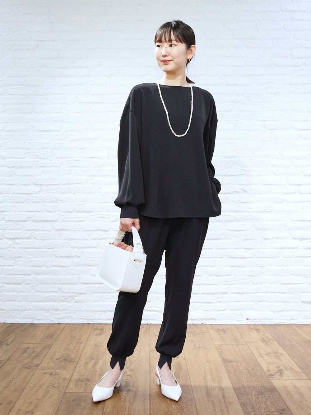 ホワイト系のハンドバッグ、ブラック系のその他パンツ、ブラック系のシャツ/ブラウスを着用したレディースの冬コーディネートの1枚目の写真