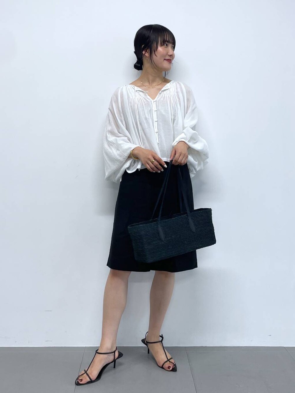 ブラック系のかごバッグ、ホワイト系のシャツ/ブラウス、ブラック系のサンダルを着用したレディースの夏コーディネートの1枚目の写真