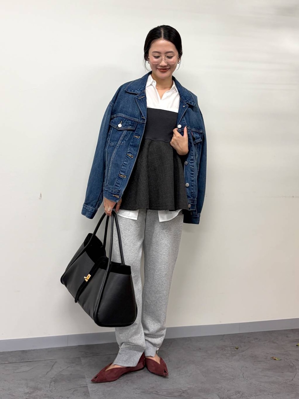 レッド系のパンプス、グレー系のスウェットパンツ、ブラック系のボストンバッグを着用したレディースの秋コーディネートの1枚目の写真