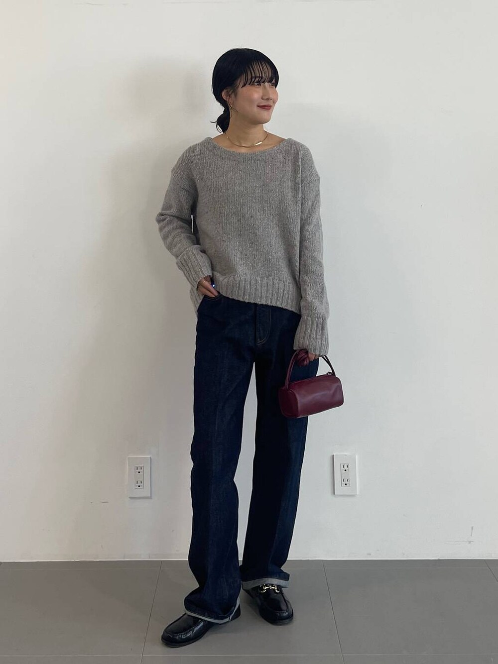 レッド系のショルダーバッグ、ブラック系のローファー、ブルー系のデニムパンツを着用したレディースの冬コーディネートの1枚目の写真