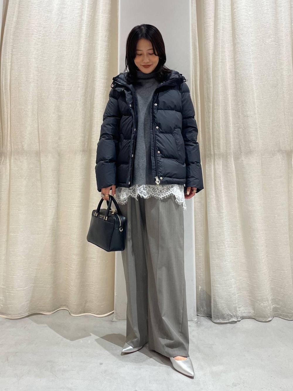 グレー系のスラックス、グレー系のニット/セーター、ホワイト系のキャミソールを着用したレディースの秋コーディネートの1枚目の写真