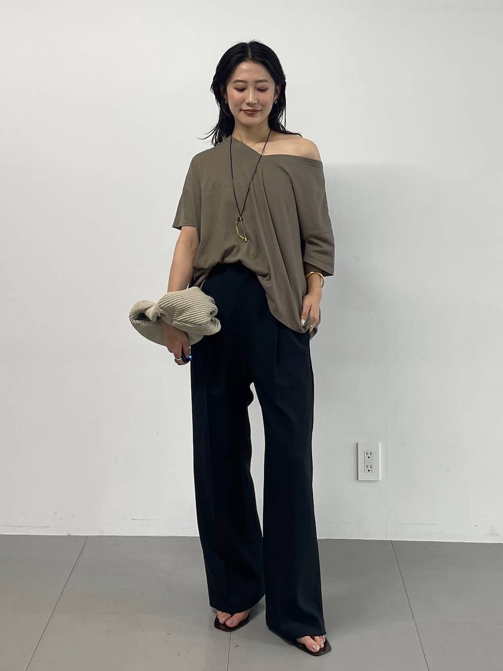 ブラック系のスラックス、グリーン系のTシャツ/カットソー、ブラック系のサンダルを着用したレディースの夏コーディネートの1枚目の写真