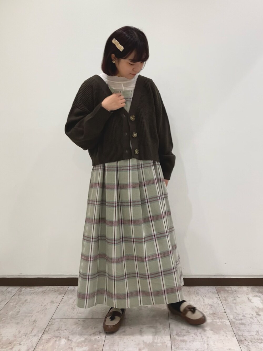 ベージュ系のカーディガン/ボレロ、グリーン系のジャンパースカート、ホワイト系のTシャツ/カットソーを着用したレディースの冬コーディネートの1枚目の写真