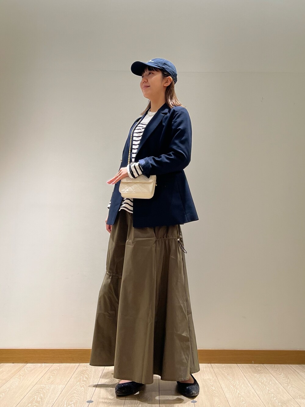 グリーン系のスカート、ブラック系のTシャツ/カットソー、ホワイト系のショルダーバッグを着用したレディースの春コーディネートの1枚目の写真
