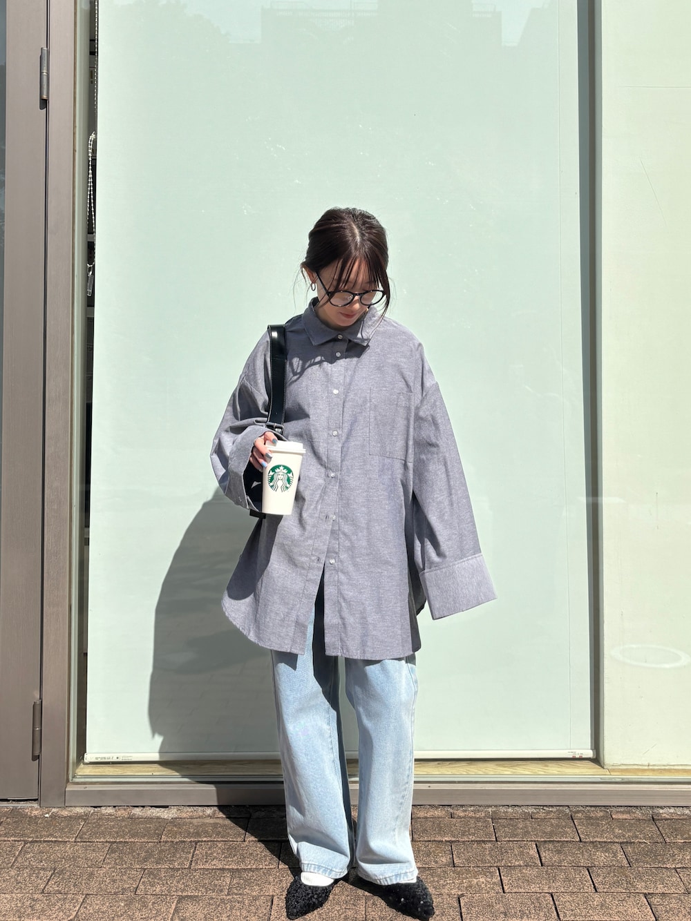 ブラック系のシャツ/ブラウス、ブルー系のデニムパンツを着用したレディースの春コーディネートの1枚目の写真