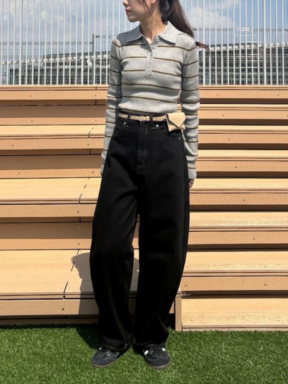 ブラック系のデニムパンツ、グレー系のニット/セーター、ブラック系のスニーカーを着用したレディースの秋コーディネートの1枚目の写真