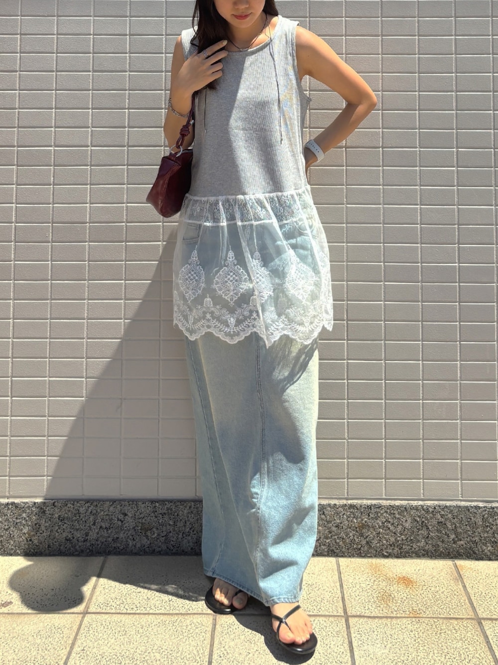 グレー系のタンクトップ、ブルー系のデニムスカート、レッド系のハンドバッグを着用したレディースの夏コーディネートの1枚目の写真