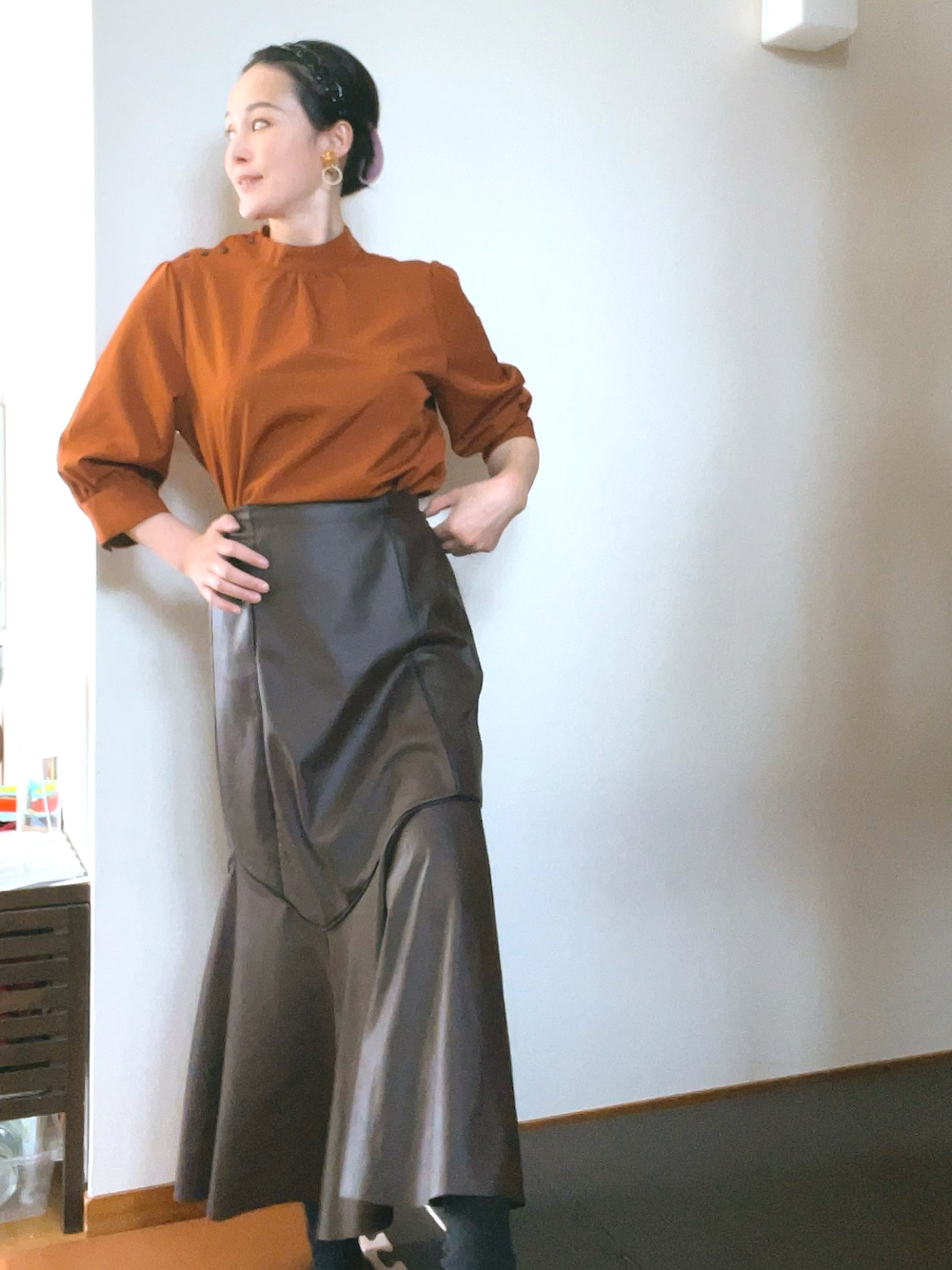 ブラウン系のシャツ/ブラウス、ブラウン系のスカート、ゴールド系のイヤリングを着用したレディースの春コーディネートの1枚目の写真