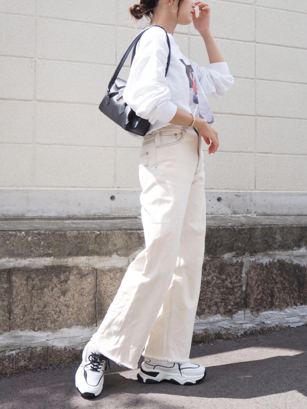 ブラック系のハンドバッグ、ブラック系のスニーカーを着用したレディースの秋コーディネートの1枚目の写真