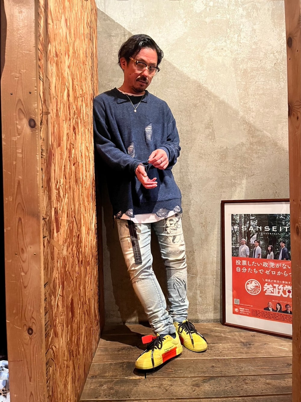 ブルー系のデニムパンツ、イエロー系のスニーカー、ブルー系のニット/セーターを着用したメンズの春コーディネートの1枚目の写真
