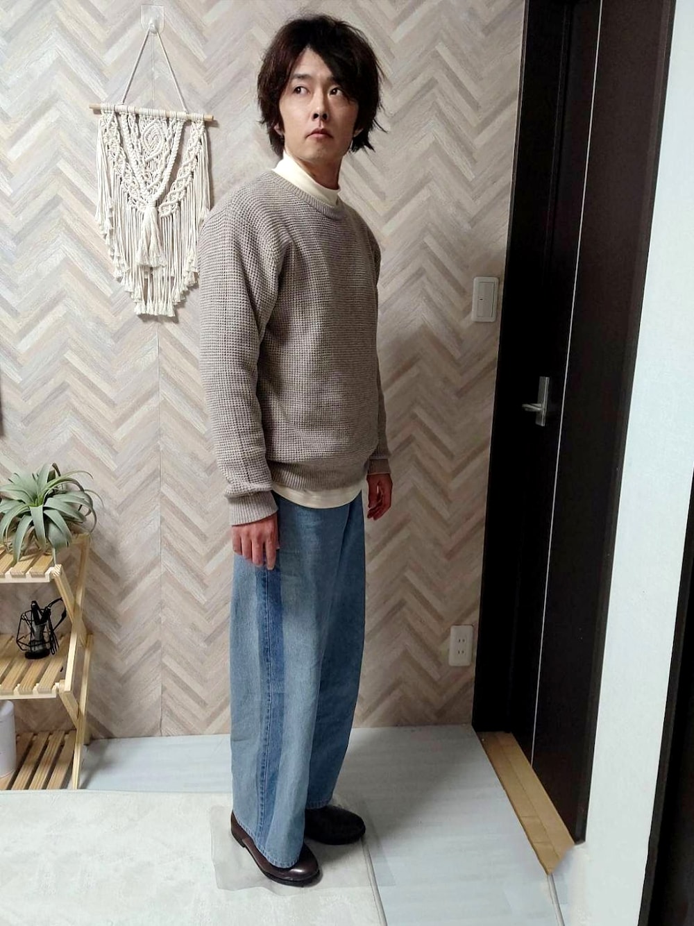 ブラウン系のスリッポン、ブルー系のデニムパンツ、ベージュ系のニット/セーターを着用したメンズの冬コーディネートの1枚目の写真