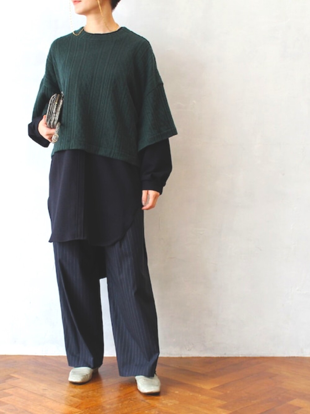 グリーン系のニット/セーター、ブルー系のスラックス、グレー系のドレスシューズを着用したレディースの秋コーディネートの1枚目の写真