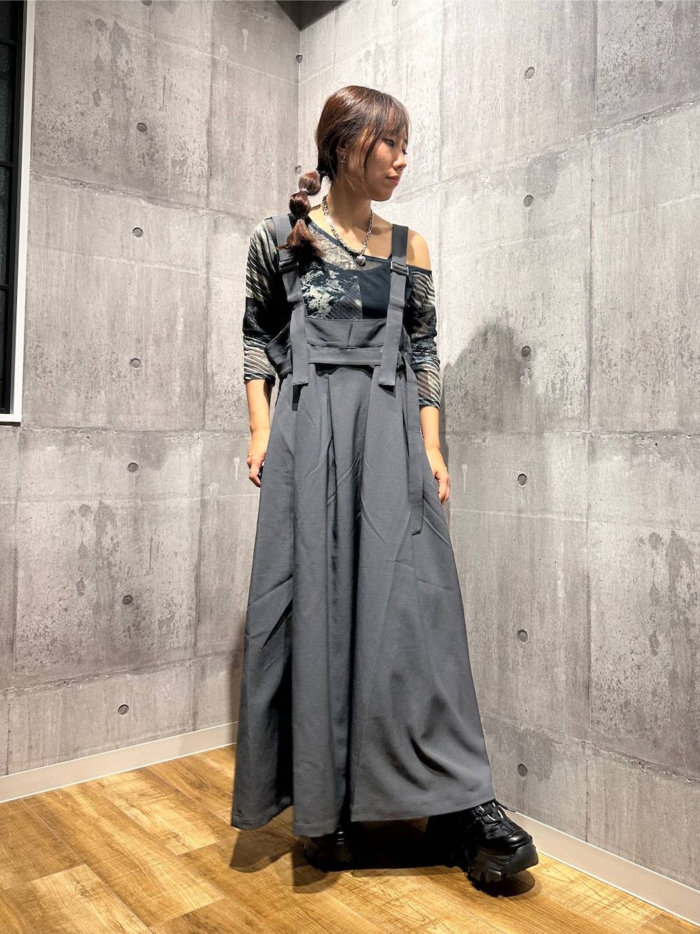 グレー系のジャンパースカート、ブラック系のスニーカー、グレー系のTシャツ/カットソーを着用したレディースの秋コーディネートの1枚目の写真