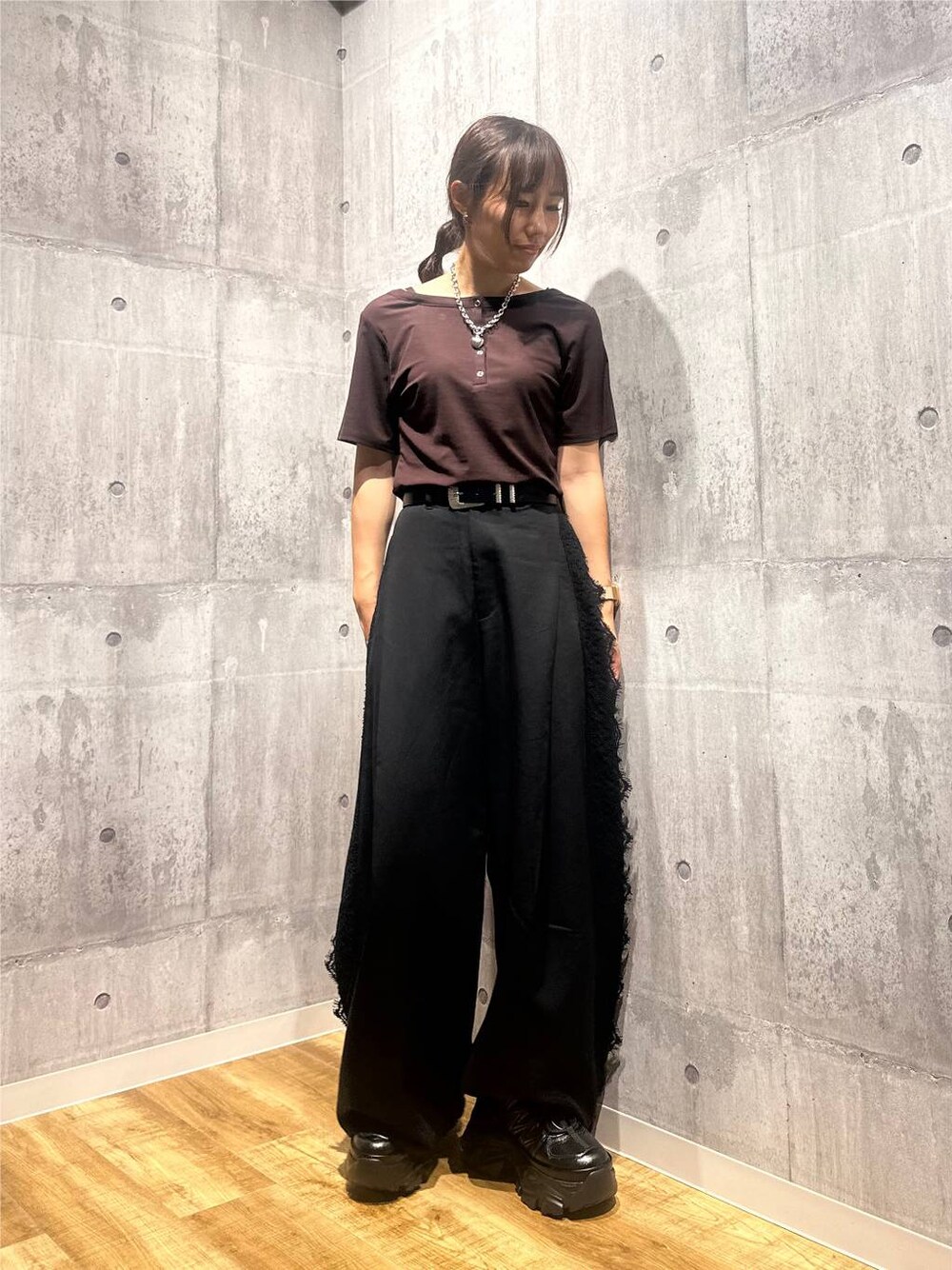 ブラウン系のTシャツ/カットソー、ブラック系のスラックス、ブラック系のスニーカーを着用したレディースの秋コーディネートの1枚目の写真
