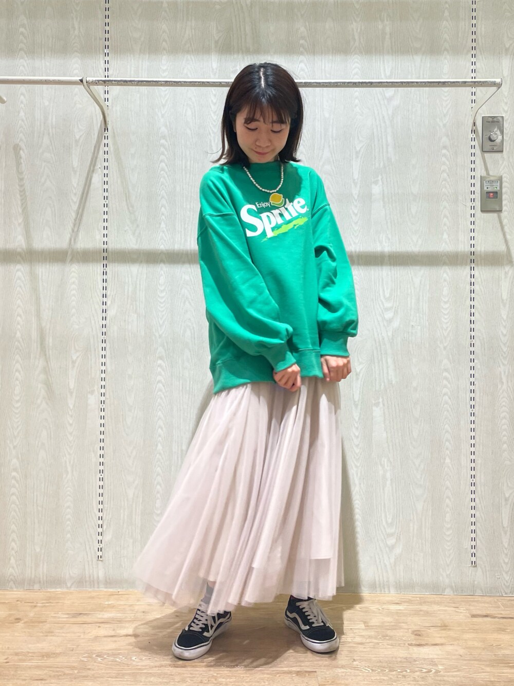 ベージュ系のスカート、グリーン系のスウェットを着用したレディースの春コーディネートの1枚目の写真