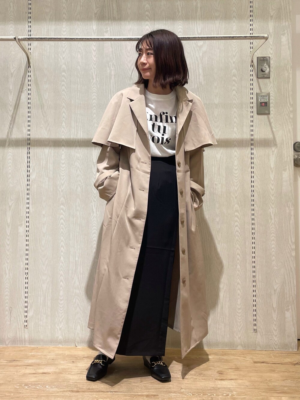 ブラック系のシャツ/ブラウス、ブラック系のスカート、ベージュ系のトレンチコートを着用したレディースの冬コーディネートの1枚目の写真