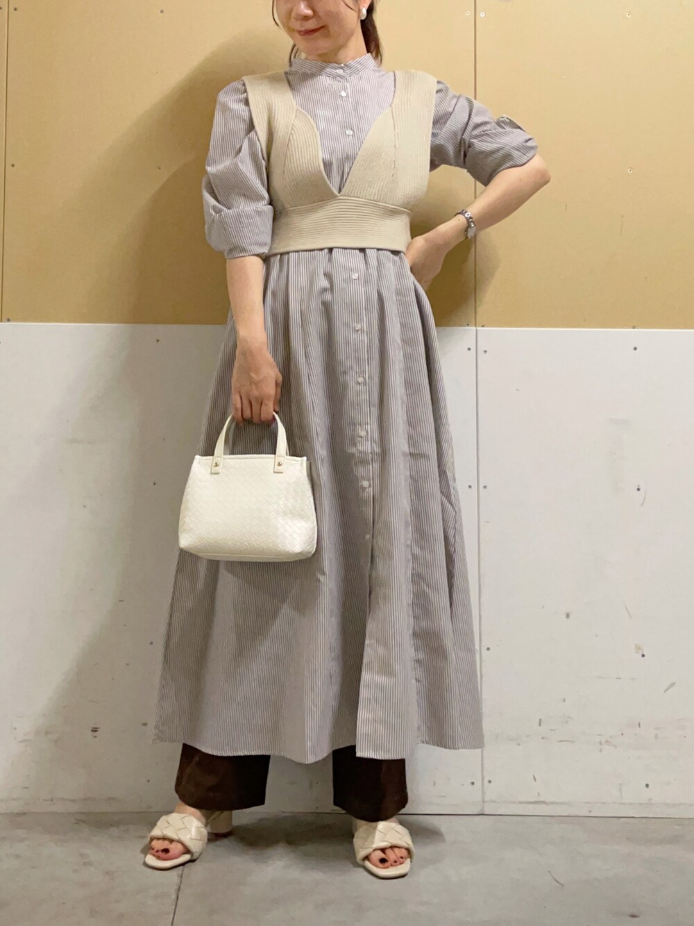 ホワイト系のトートバッグ、ベージュ系のベスト、ベージュ系のシャツワンピースを着用したレディースの夏コーディネートの1枚目の写真