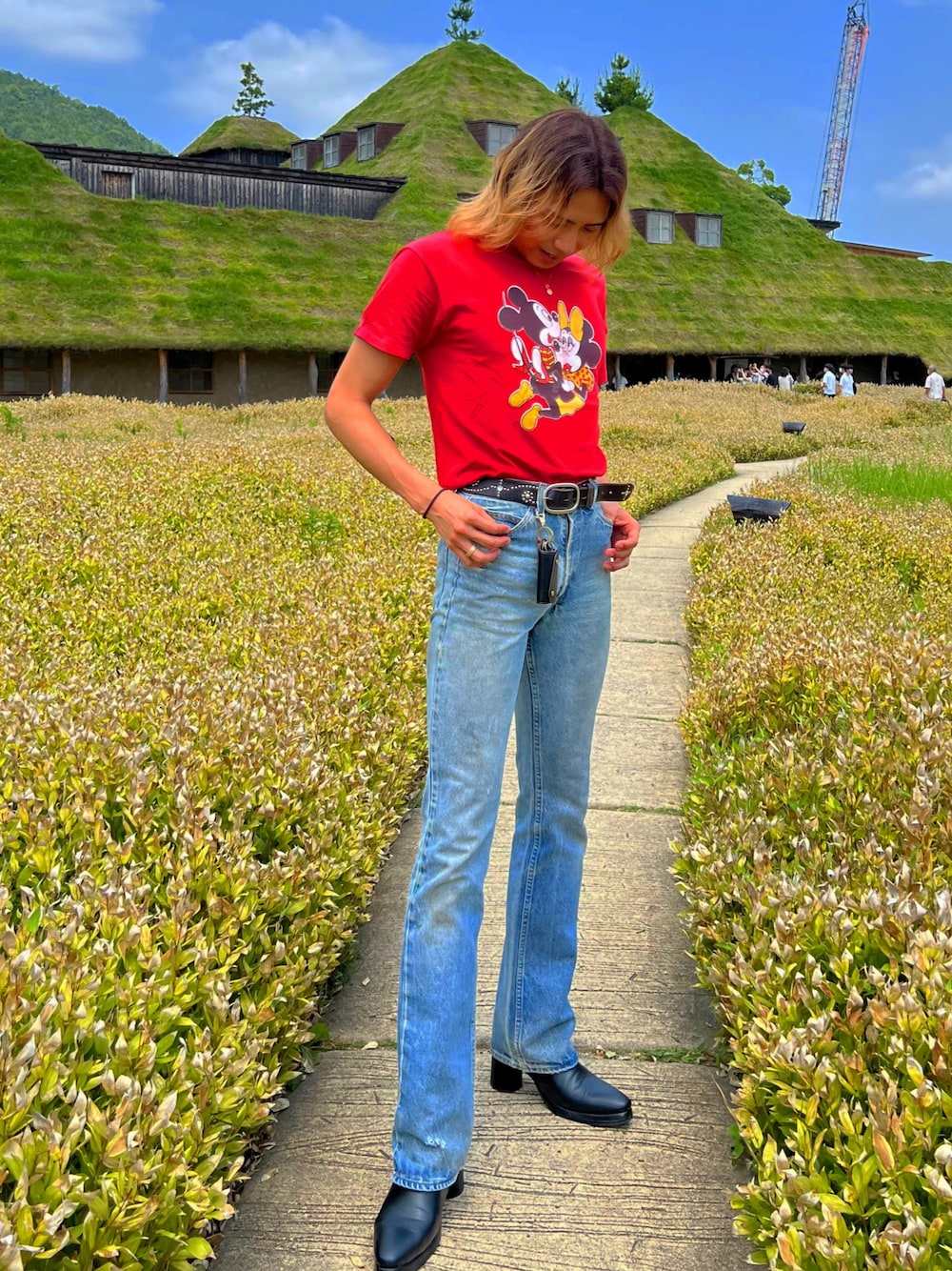 ブルー系のデニムパンツ、レッド系のTシャツ/カットソー、ブラック系のブーツを着用したメンズの夏コーディネートの1枚目の写真