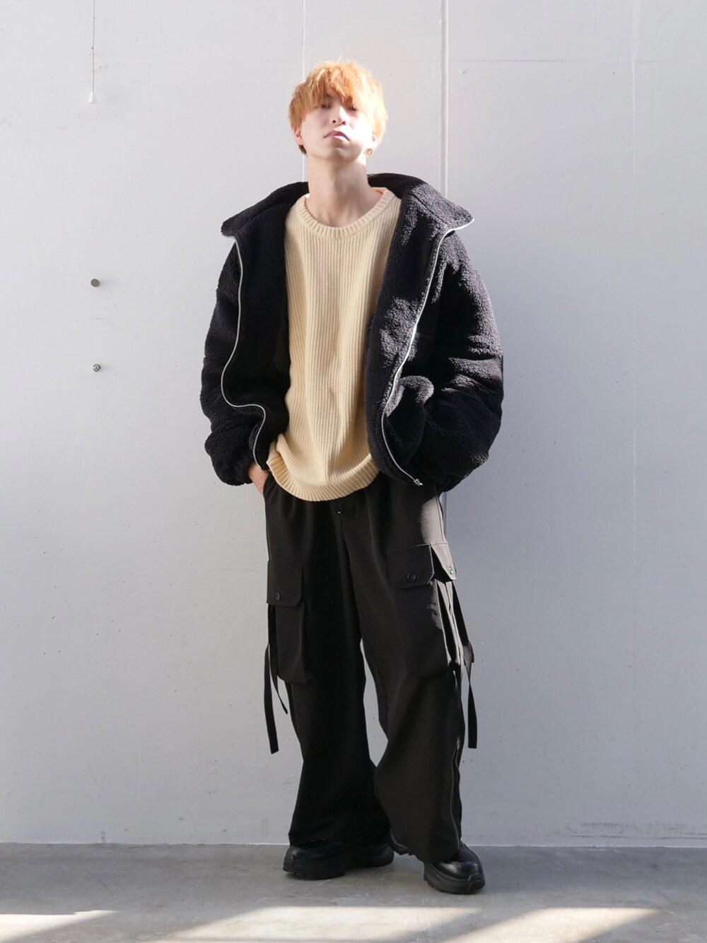 ブラック系のブルゾン、ホワイト系のニット/セーター、ブラック系のカーゴパンツを着用したメンズの秋コーディネートの1枚目の写真