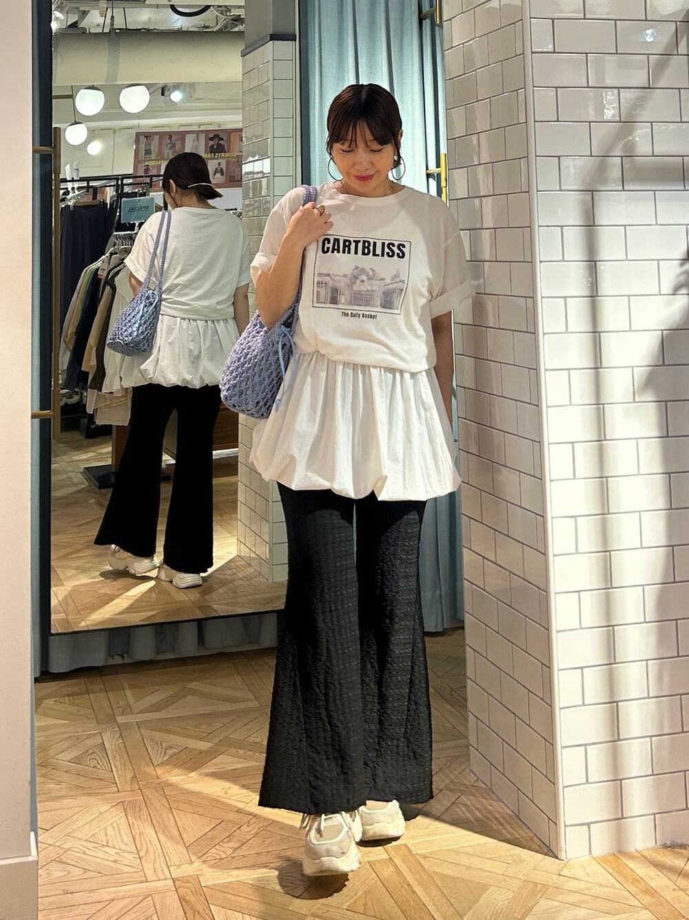 ブルー系のトートバッグ、ホワイト系のTシャツ/カットソー、ベージュ系のスニーカーを着用したレディースの春コーディネートの1枚目の写真