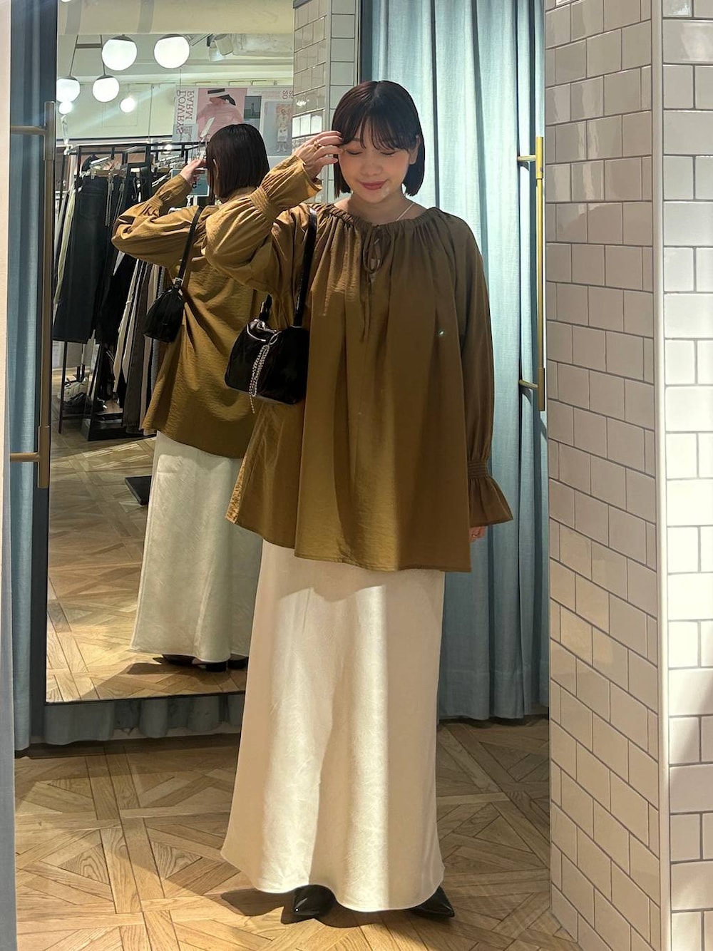 ブラック系のトートバッグ、ブラック系のパンプス、ベージュ系のシャツ/ブラウスを着用したレディースの春コーディネートの1枚目の写真