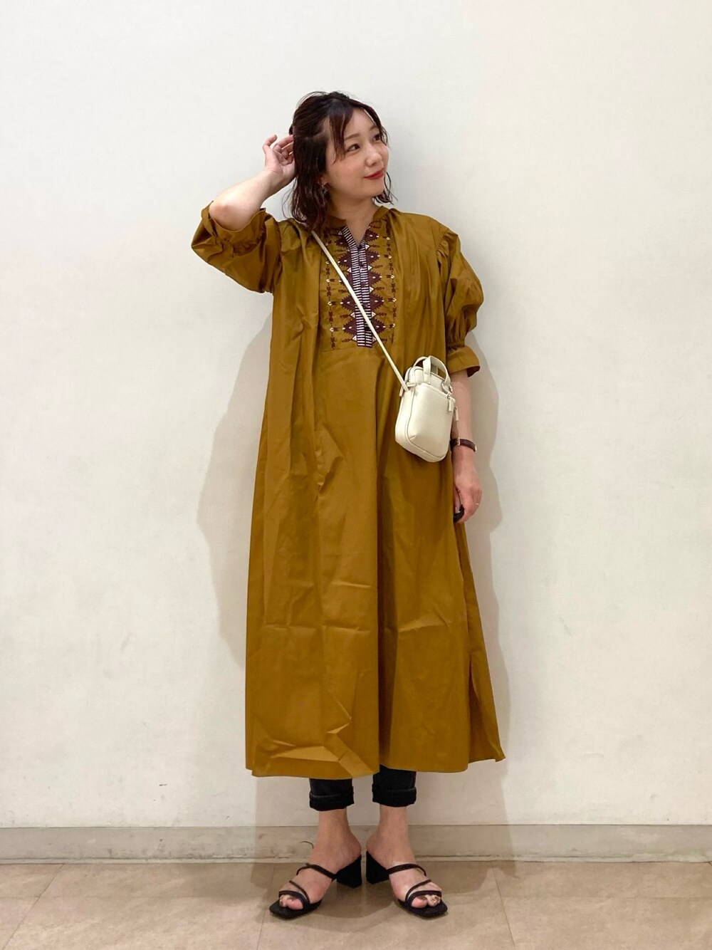 ブラウン系のワンピース、ホワイト系のショルダーバッグ、ブラック系のサンダルを着用したレディースの春コーディネートの1枚目の写真