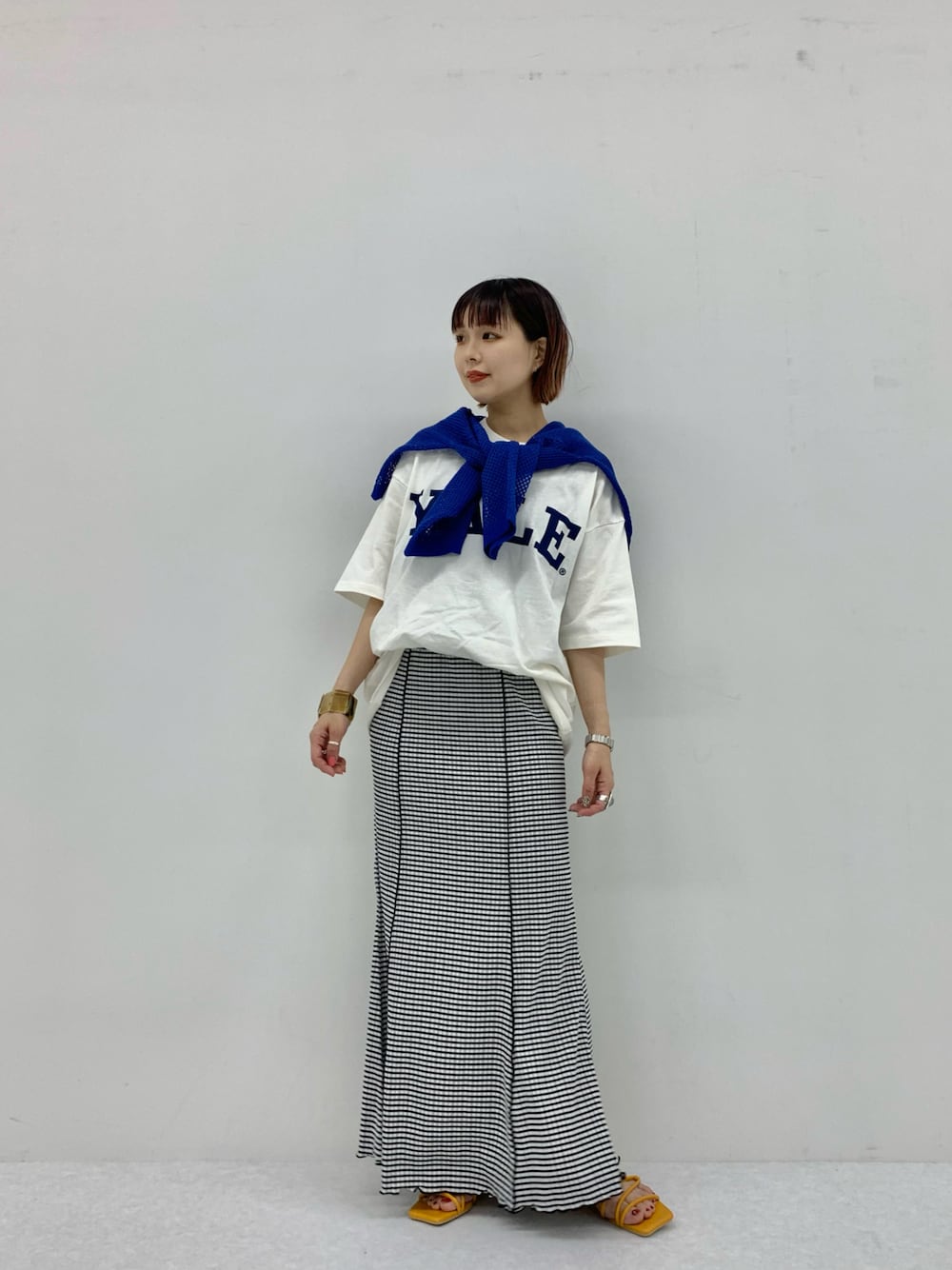 グリーン系のスカート、ホワイト系のTシャツ/カットソー、イエロー系のサンダルを着用したレディースの夏コーディネートの1枚目の写真