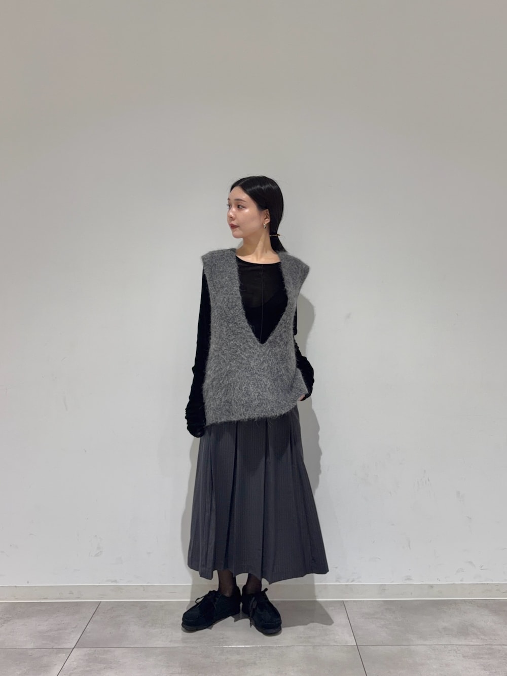ブラック系のTシャツ/カットソー、グレー系のスカート、ブラック系のブーツを着用したレディースの秋コーディネートの1枚目の写真