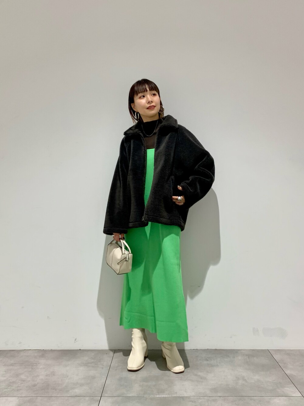 グリーン系のワンピース、グレー系のブルゾン、ブラック系のブーツを着用したレディースの冬コーディネートの1枚目の写真