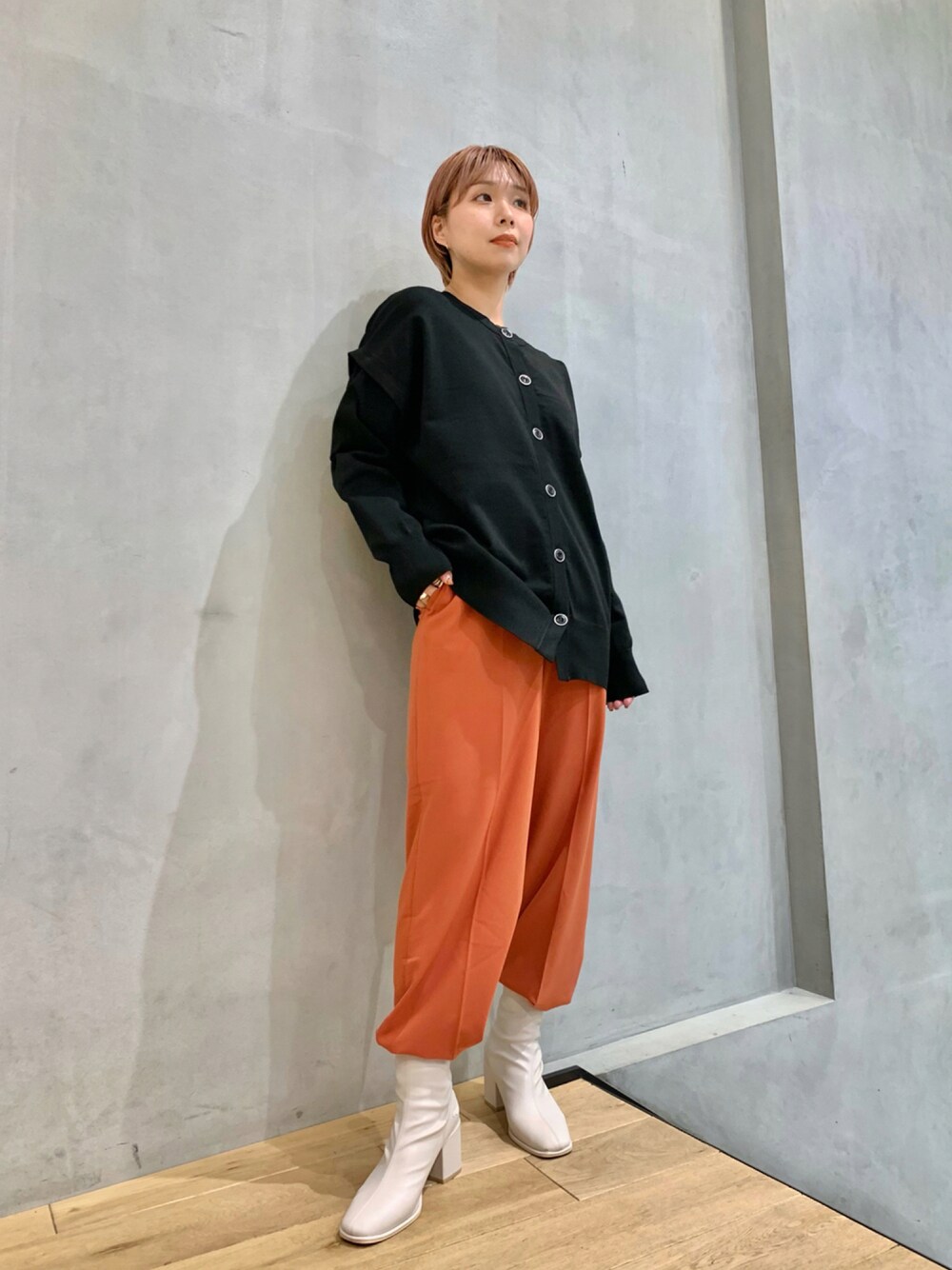 ブラック系のカーディガン/ボレロ、オレンジ系のその他パンツ、ホワイト系のブーツを着用したレディースの秋コーディネートの1枚目の写真