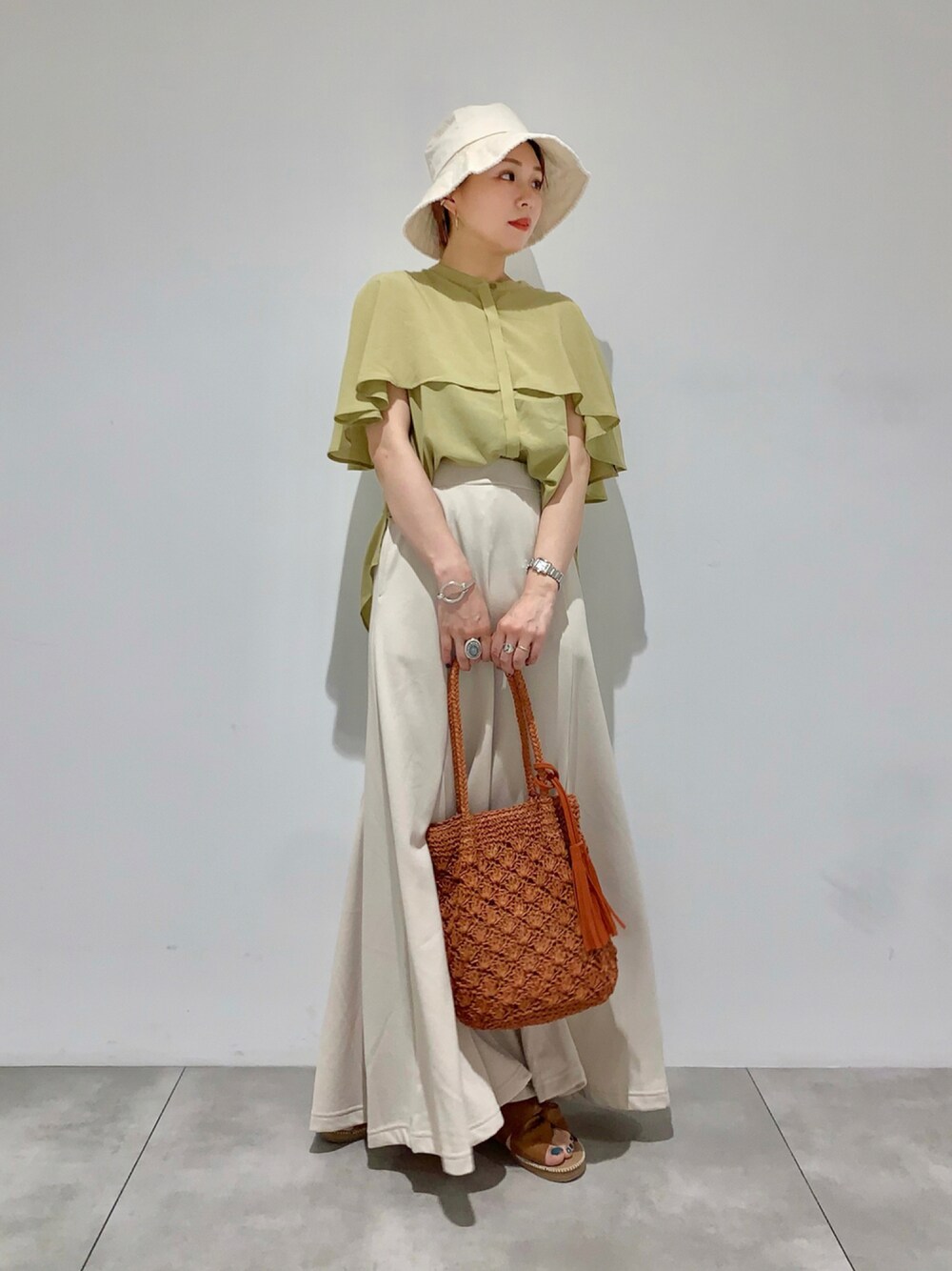 イエロー系のシャツ/ブラウス、ホワイト系のスカート、オレンジ系のショルダーバッグを着用したレディースの夏コーディネートの1枚目の写真