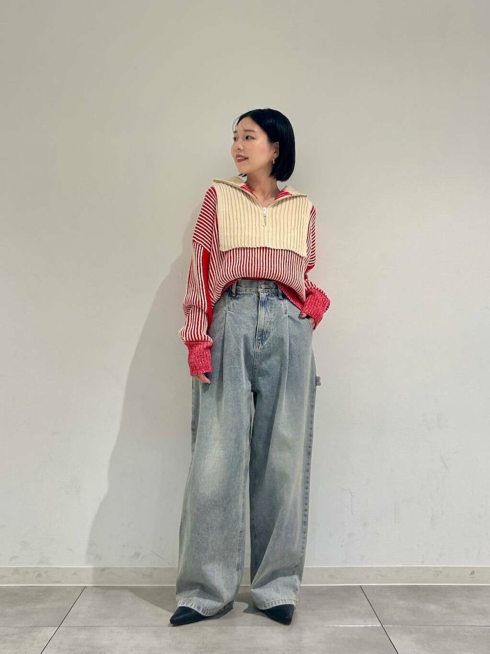 レッド系のニット/セーター、ブルー系のデニムパンツ、ブラック系のブーツを着用したレディースの冬コーディネートの1枚目の写真